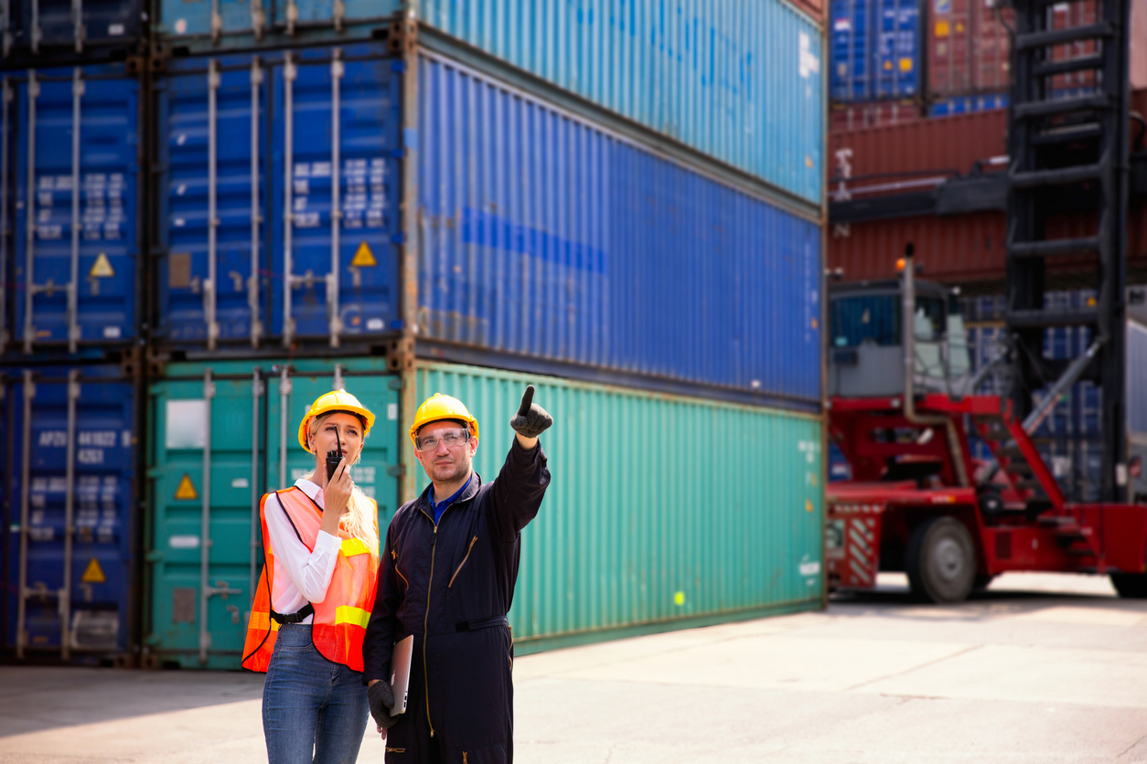 Businesswoman using a radio and talking with a logistics partner to handle operations.