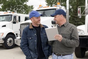 Business owner of a logistics company speaking with a male truck driver about his delivery itineraries.